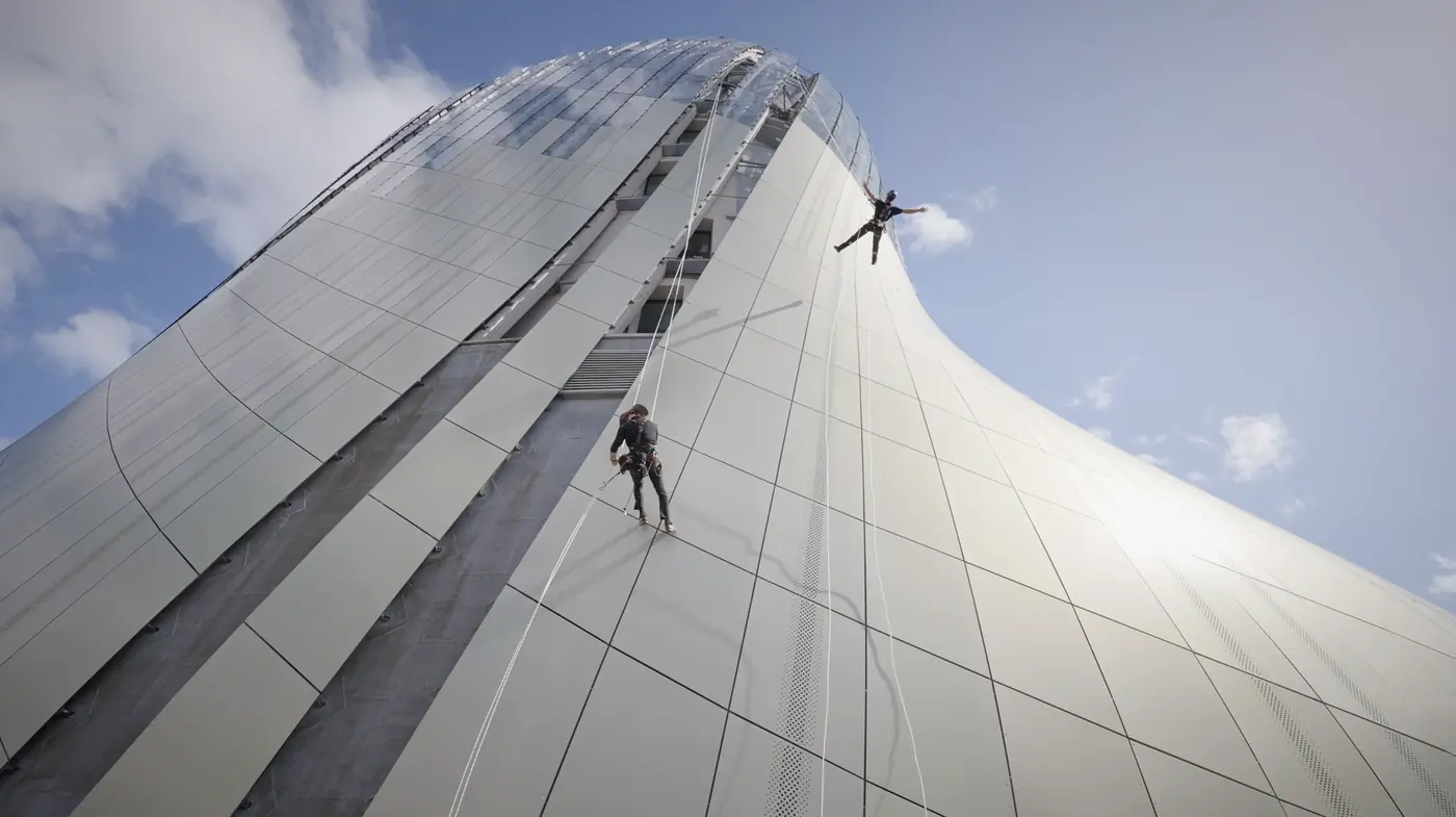 marathon du vertige Deux cordistes en rappel sur la façade courbe de la Cité du Vin, sous un ciel bleu.