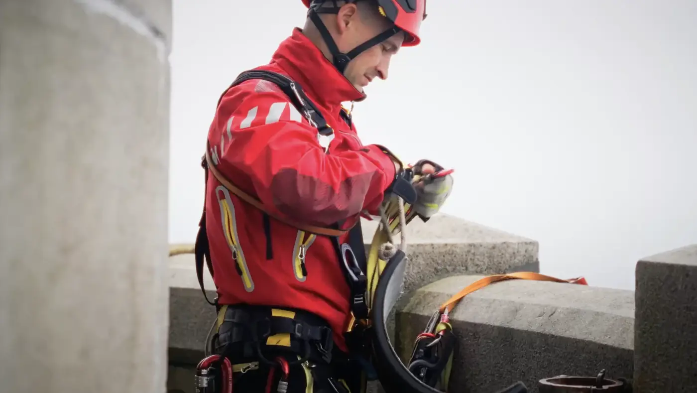 marathon du vertige Un secouriste en tenue rouge prépare son équipement de rappel en haut du phare.