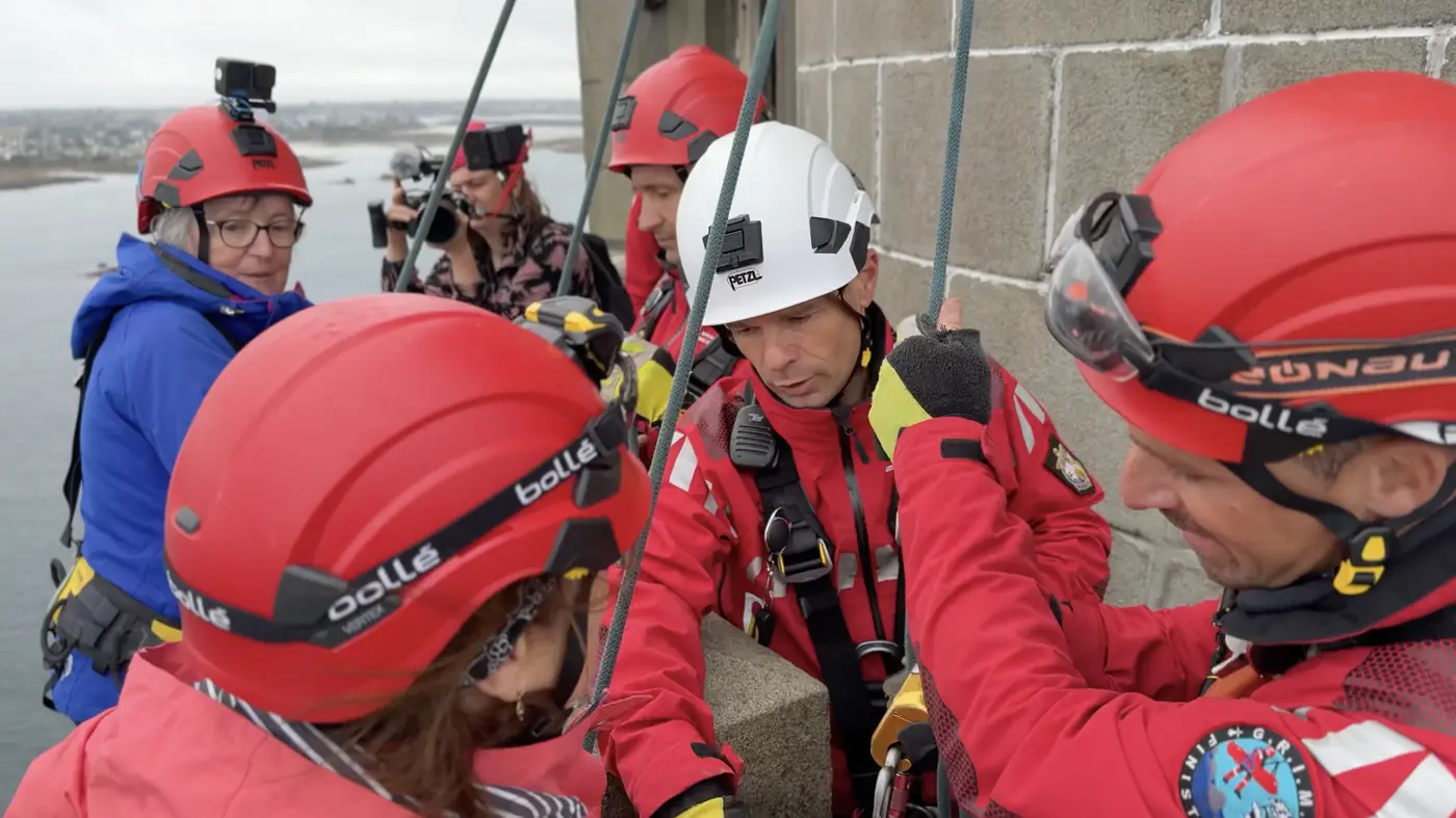 marathon du vertige Une équipe de secouristes en tenue rouge et casques ajuste le matériel de rappel au sommet du phare.